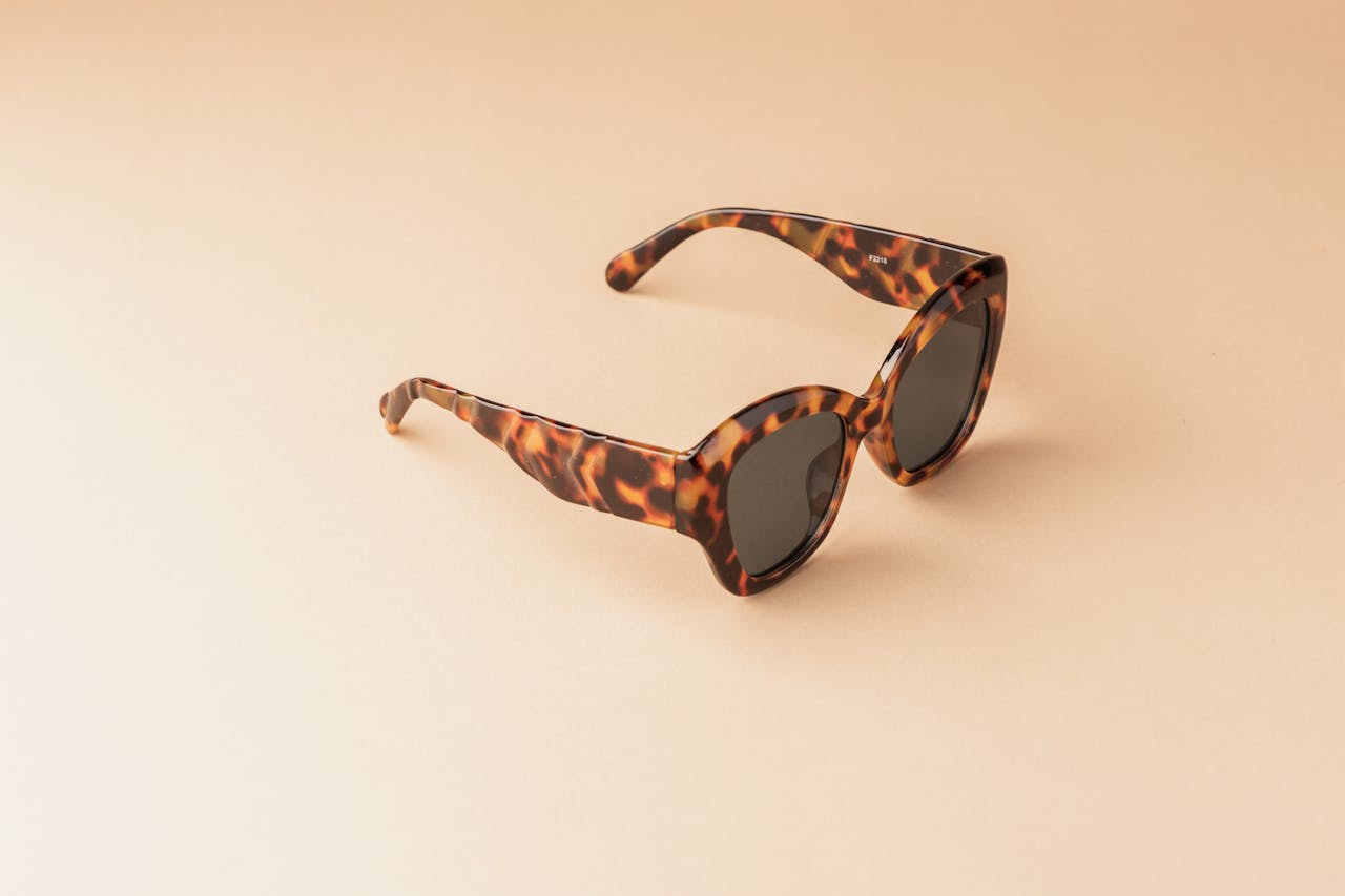 Elegant tortoiseshell sunglasses with dark lenses on a beige background, perfect for fashion or summer themes.